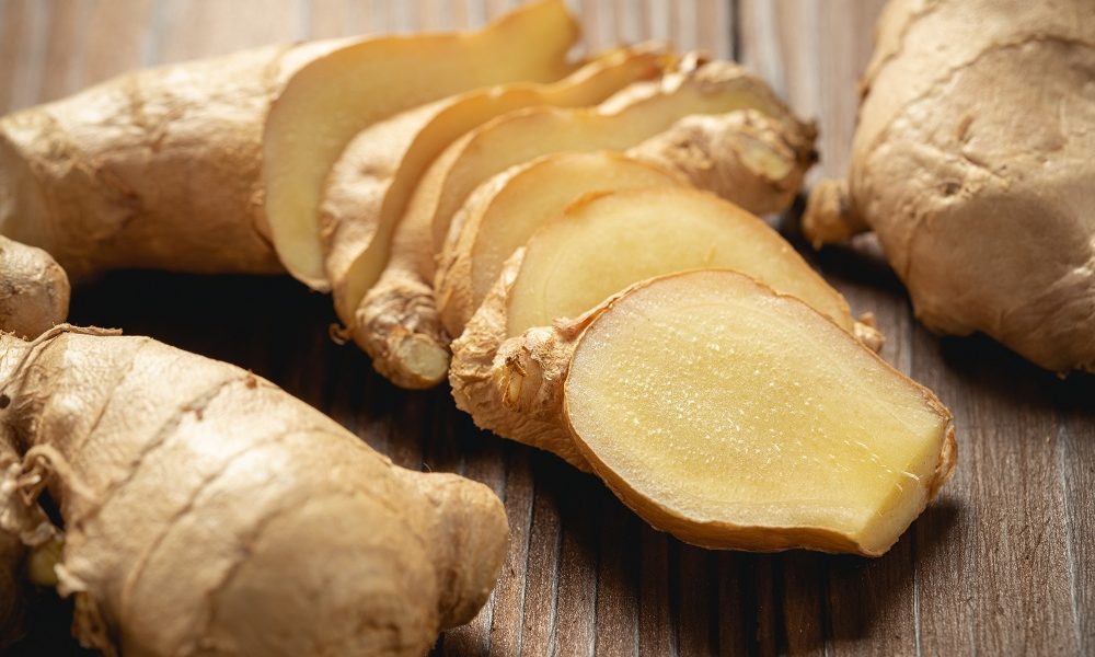 Fresh ginger root and sliced on wooden table.